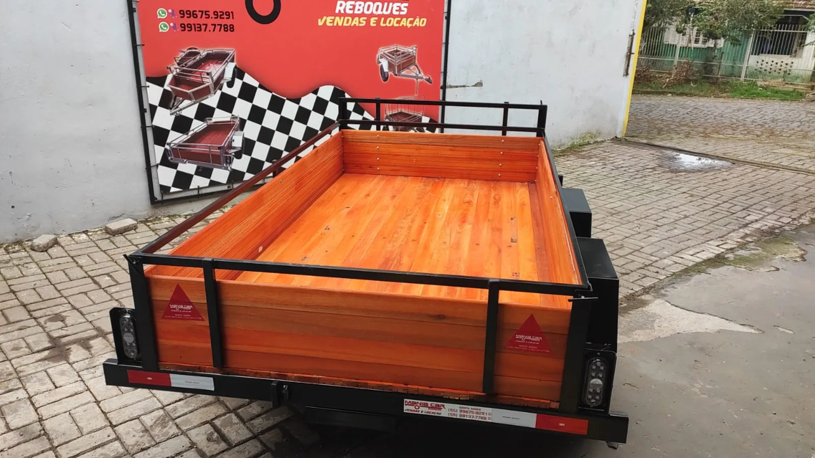 Carretinha de um eixo com laterais de madeira estacionada no pátio da loja